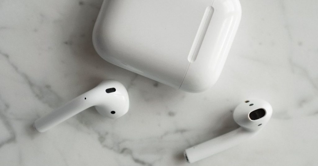 High-quality image of wireless earbuds and charging case on marble surface, showcasing modern technology.