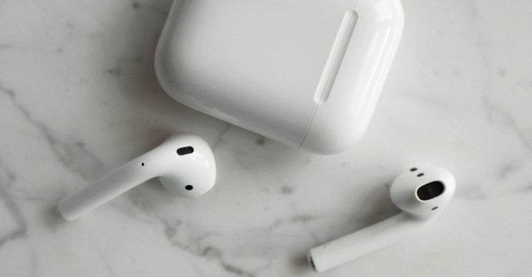 High-quality image of wireless earbuds and charging case on marble surface, showcasing modern technology.