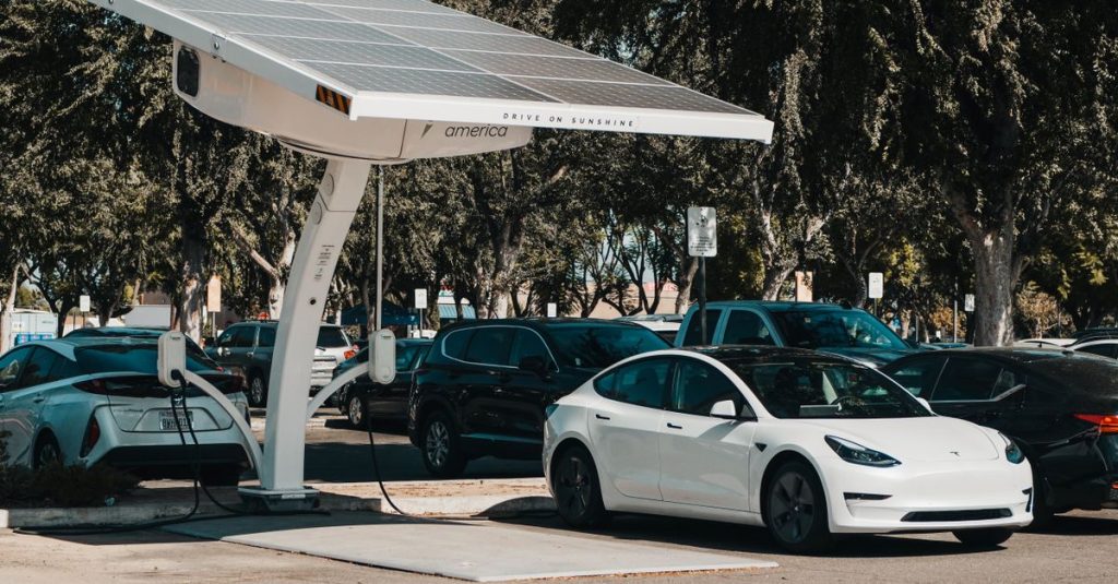 Electric car parked at a solar charging station outdoors, highlighting renewable energy and innovation.