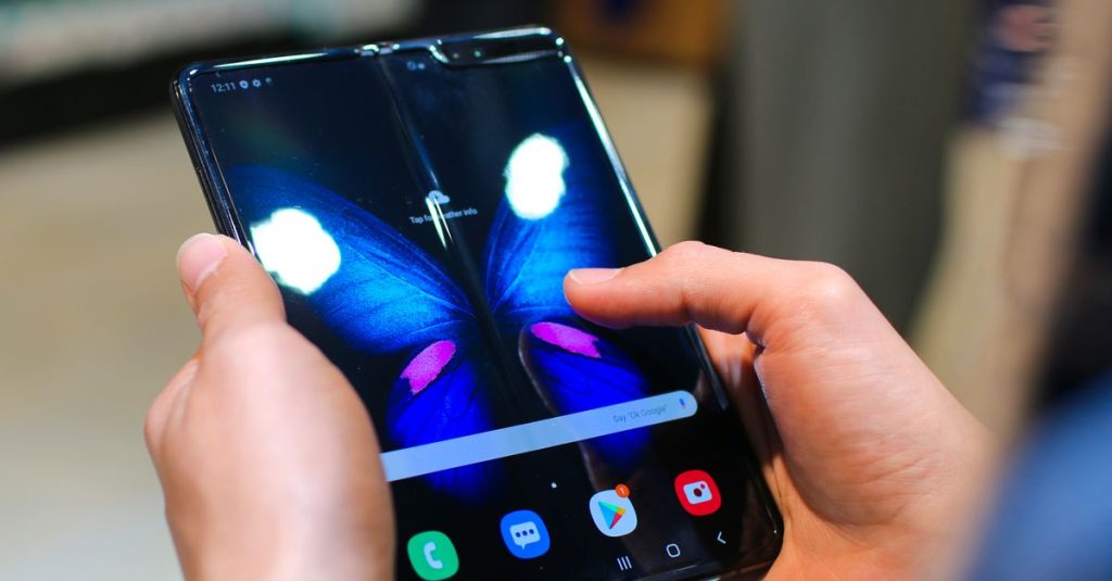 Close-up of hands holding a foldable smartphone showing a butterfly on the screen.