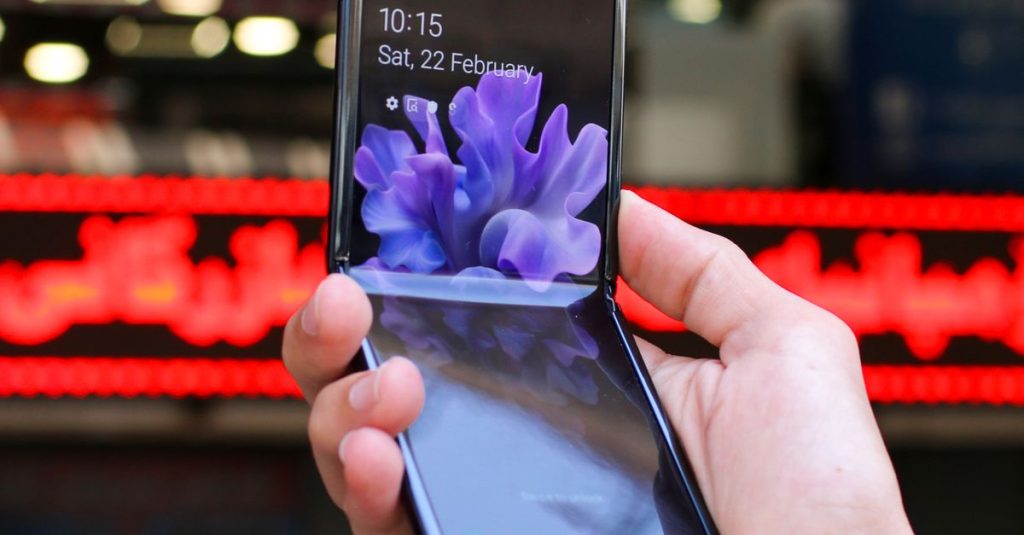 Close-up of a modern flip smartphone held in hand, showcasing innovative technology outdoors in a bustling city.