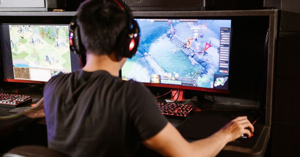 Adult male gamer immersed in PC gaming on dual monitors with headphones indoors.