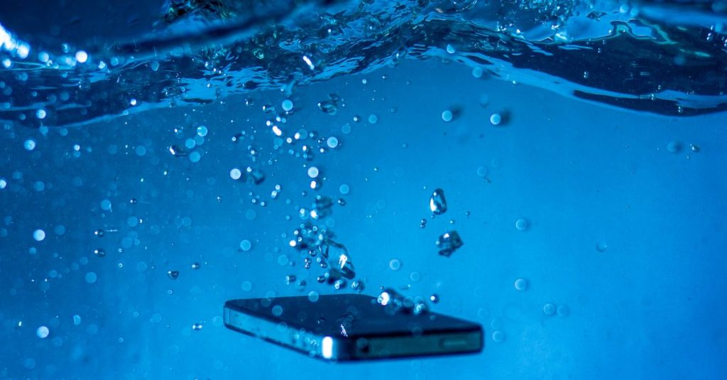 A smartphone submerged in water with bubbles rising around it, showcasing a dynamic underwater scene.