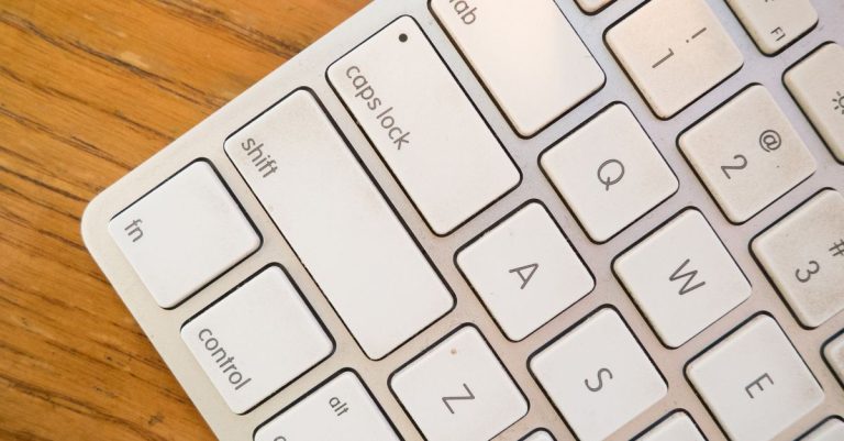 A detailed close-up of a modern computer keyboard on a wooden desk.
