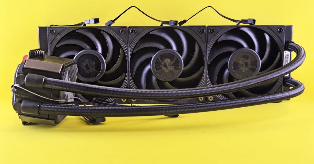Close-up of a triple fan water cooling system against a bright yellow backdrop.