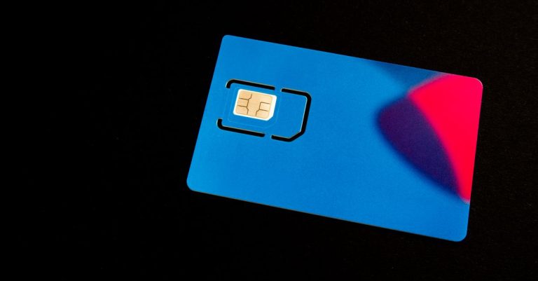 A blue SIM card on a dark background with vibrant red and purple accents.