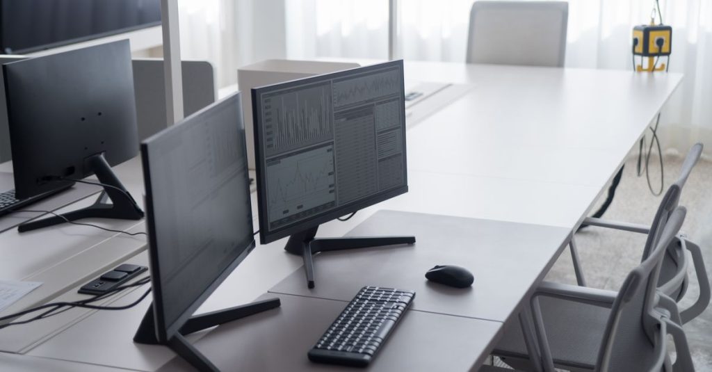 A clean and modern office desk with dual monitors and ergonomic chairs, ideal for productivity.