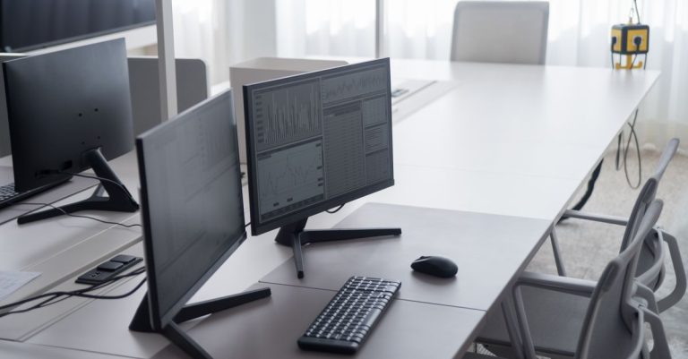 A clean and modern office desk with dual monitors and ergonomic chairs, ideal for productivity.