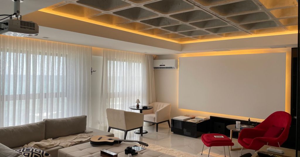 Spacious minimalist living room with natural light, featuring cozy seating and a ceiling projector.