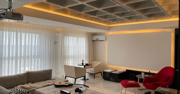 Spacious minimalist living room with natural light, featuring cozy seating and a ceiling projector.