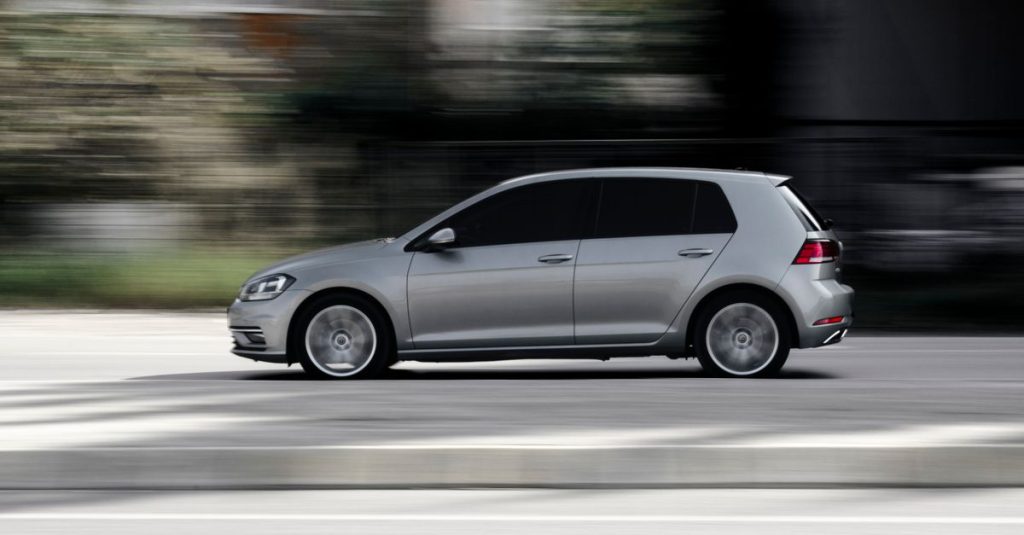 Sleek silver hatchback speeding in motion on a road, captured in a dynamic side view.