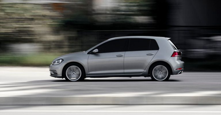 Sleek silver hatchback speeding in motion on a road, captured in a dynamic side view.