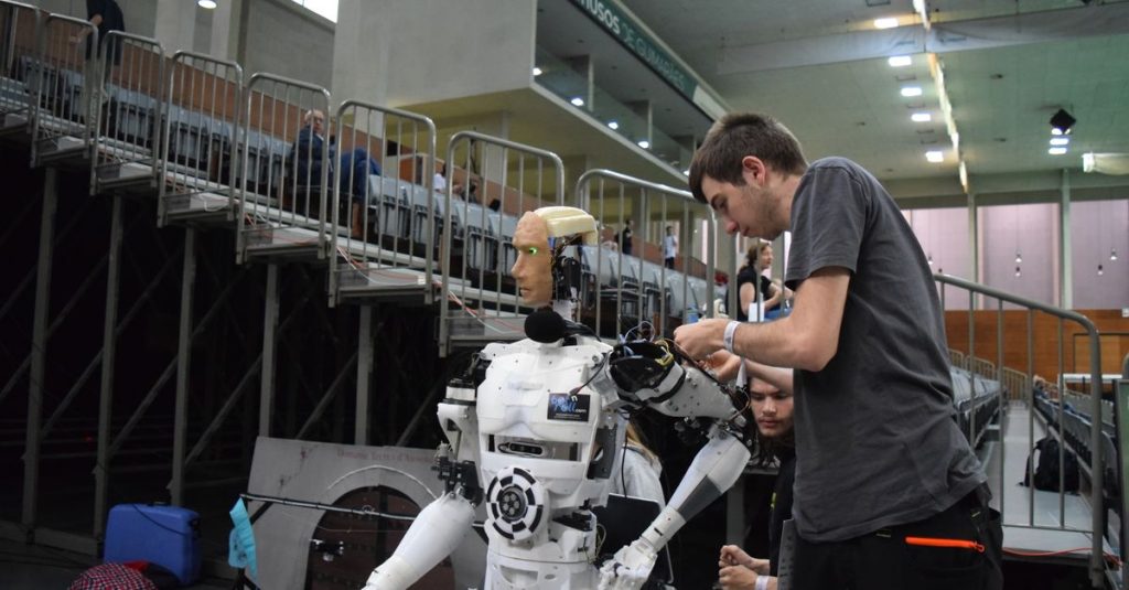 Technician working on humanoid robot at a tech exhibition in Guimaraes, Portugal.