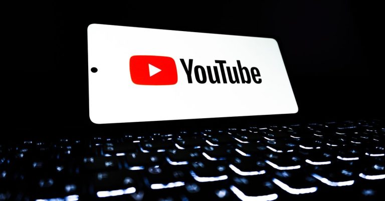 YouTube app icon displayed on a smartphone over an illuminated keyboard, representing digital media and online streaming.
