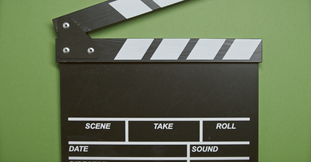 A classic film clapperboard on a green surface, essential for movie scenes.