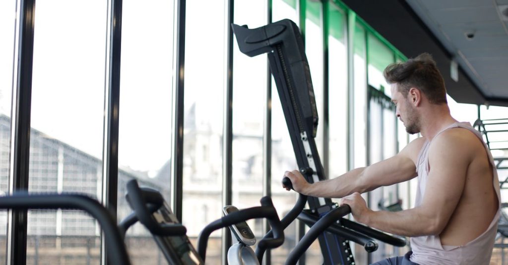 Adult man working out on a stationary bike in a modern gym, focusing on fitness and strength.
