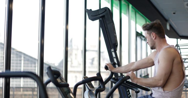 Adult man working out on a stationary bike in a modern gym, focusing on fitness and strength.
